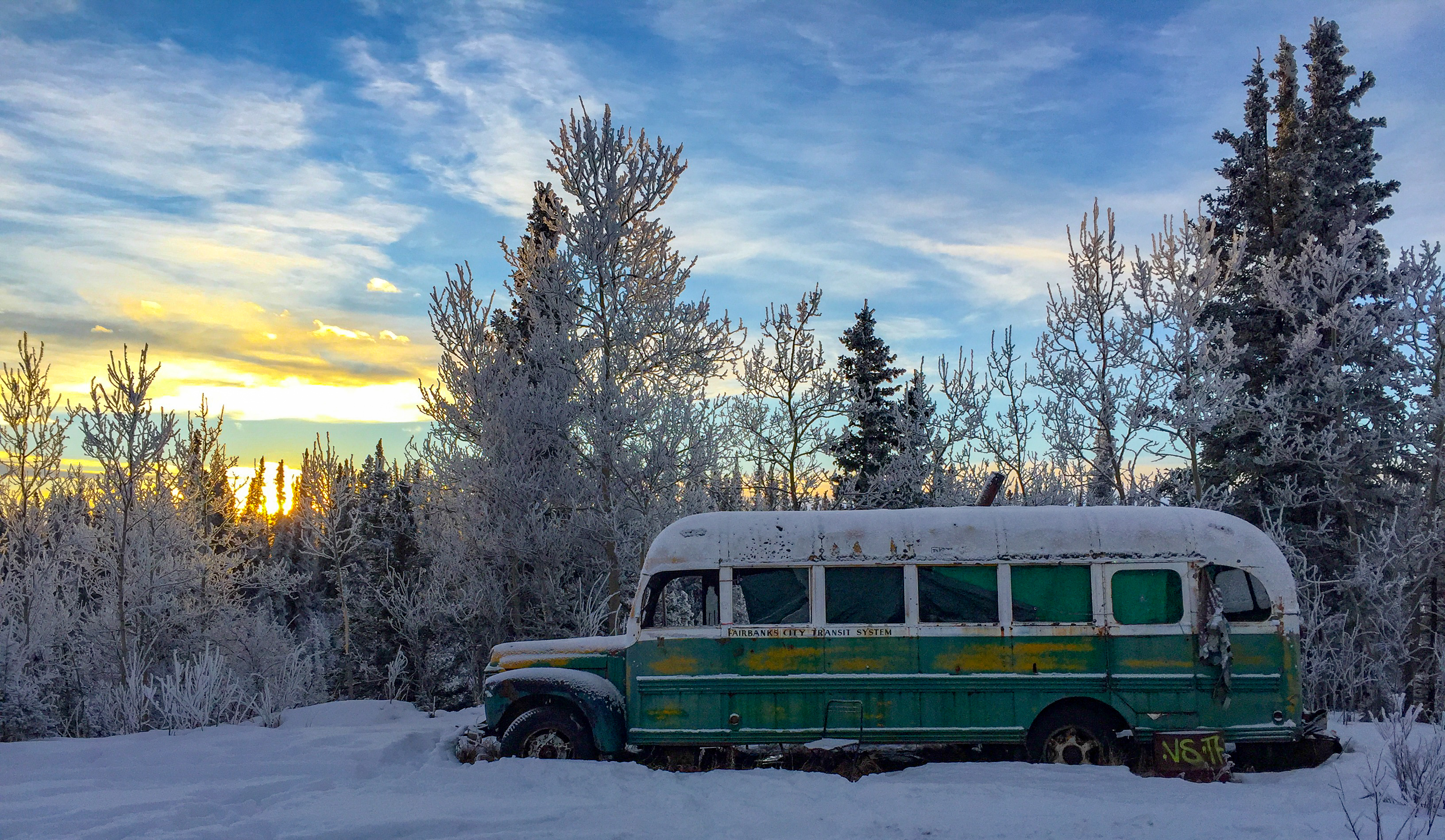 An abandoned bus in a wintery scene.